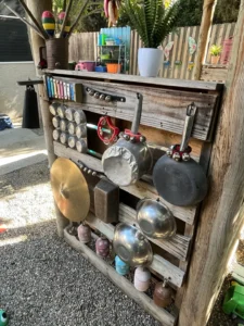 A wooden pallet with pots and pans hanging on it.