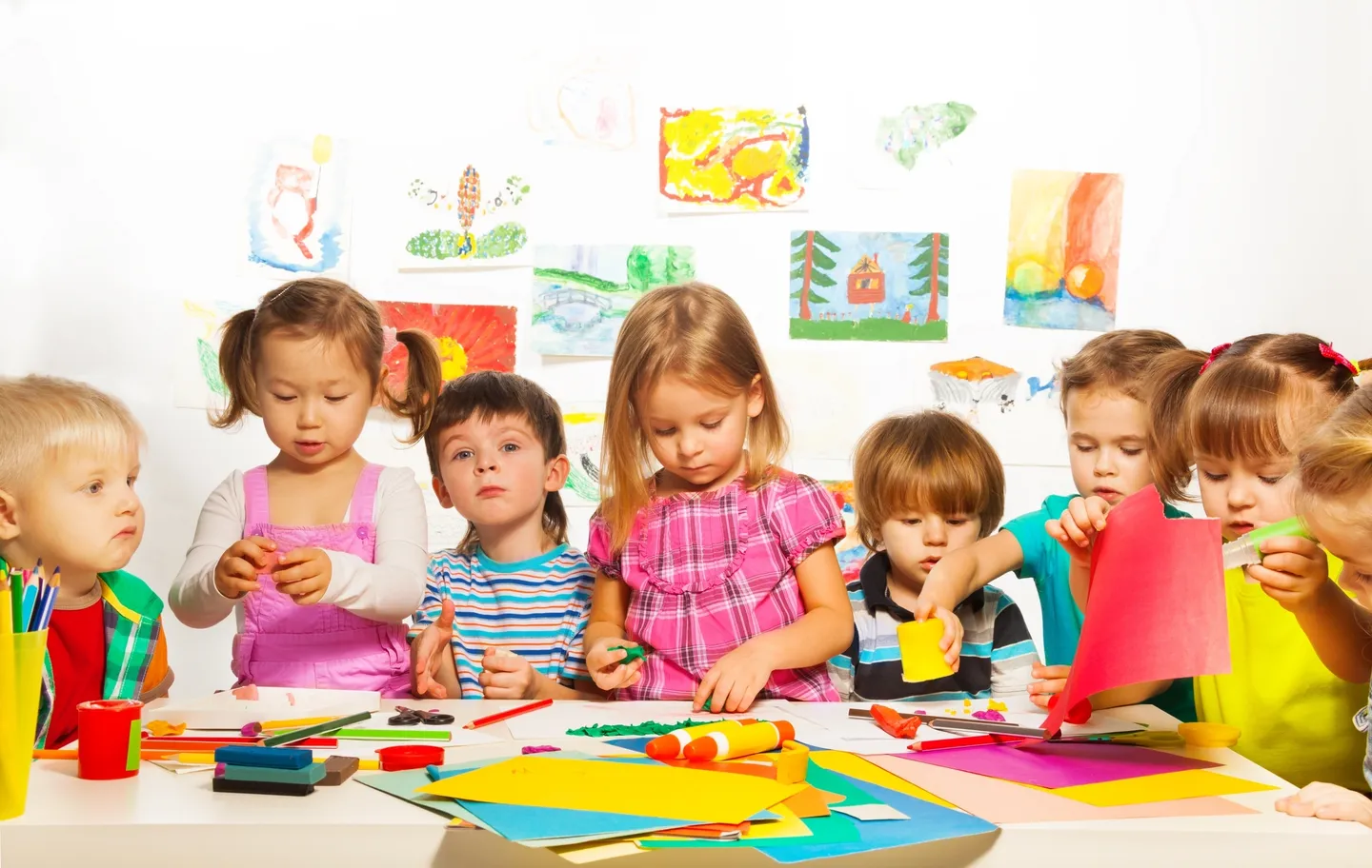 A group of children sitting at a table with paper.