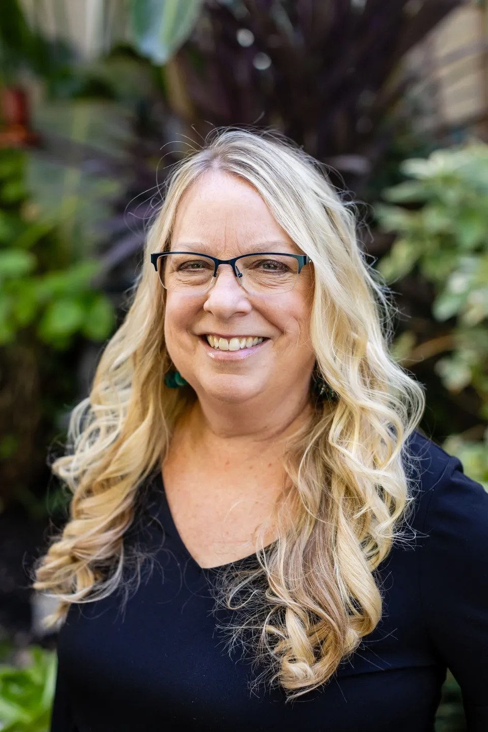 A woman with blonde hair and glasses smiling for the camera.