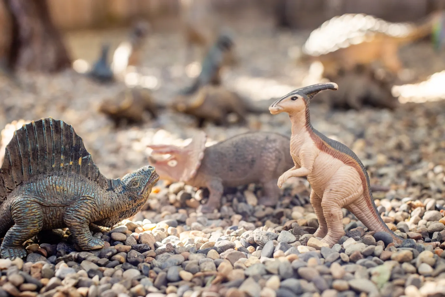 A group of toy dinosaurs on the ground.